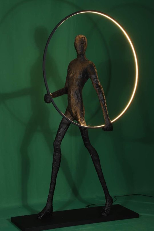 Aurora: Escultura de una figura con un círculo luminoso, simbolizando el amanecer y la salida del sol, inspirado en la diosa Aurora.